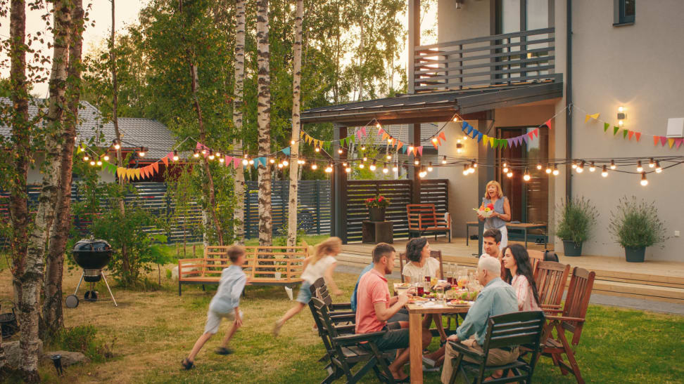 Family eating at outdoor dining set in backyard with kids playing in backyard