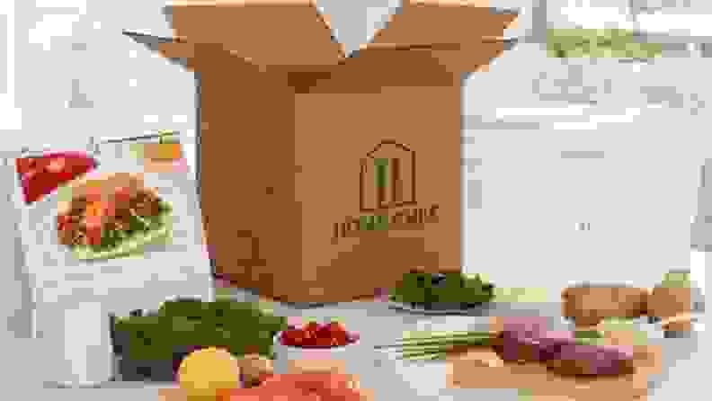 A Home Chef box on a kitchen island, with food displayed around the box.
