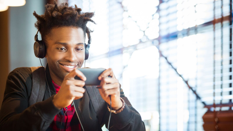 Man wearing headphones streaming a video on his phone