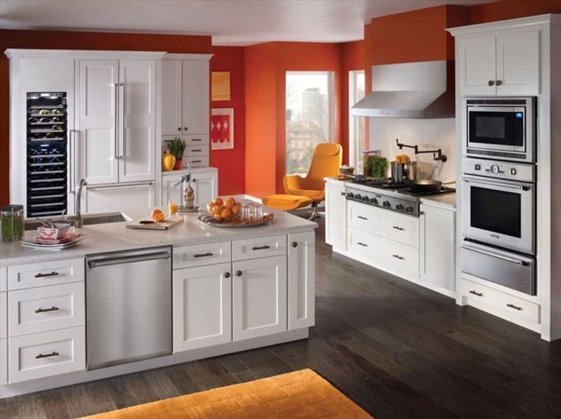 Striking contemporary orange kitchen with orange accents, outfitted with a Thermador 24-inch Sapphire series dishwasher, 48-inch rangetop, and 30-inch combination wall oven.