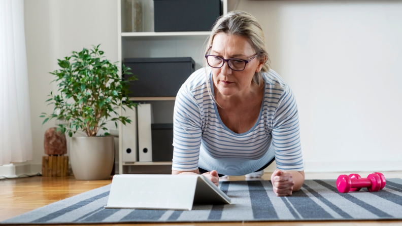 A person exercises watching a program on a tablet.