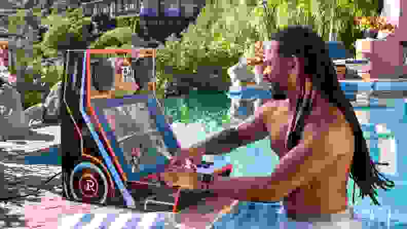 A man playing the top part of the Retromania arcade cabinet by the pool.