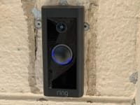 The Ring Video Doorbell Wired hangs on the front of a home.