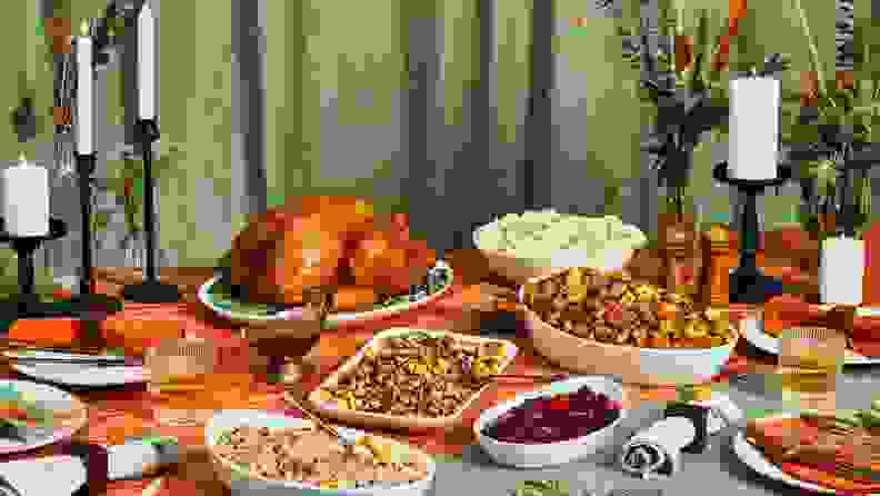 A Thanksgiving feast on an elaborately decorated table with sliced holiday turkey and various side dishes.