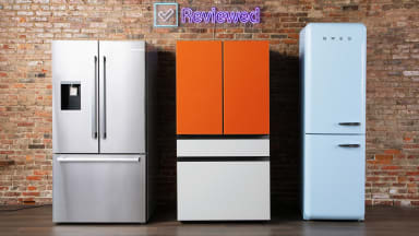 Three different refrigerators standing against a brick wall