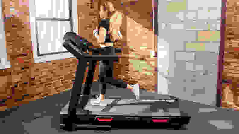 A woman runs in profile on the Bowflex BXT8J treadmill.