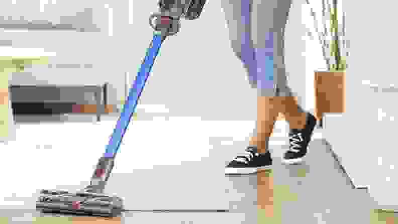woman vacuuming white rug with Dyson vacuum