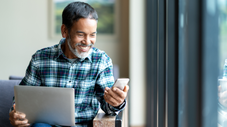 A person uses a phone and tablet to check social media.