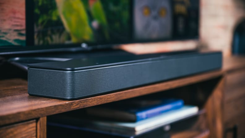 A black soundbar sits on a wood credenza.