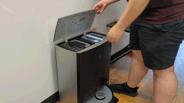A person shown removing dirty water tank from Ecovacs Deebot X1 Omni charging base.
