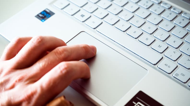 A close up of a person's fingers touching a trackpad on a laptop.