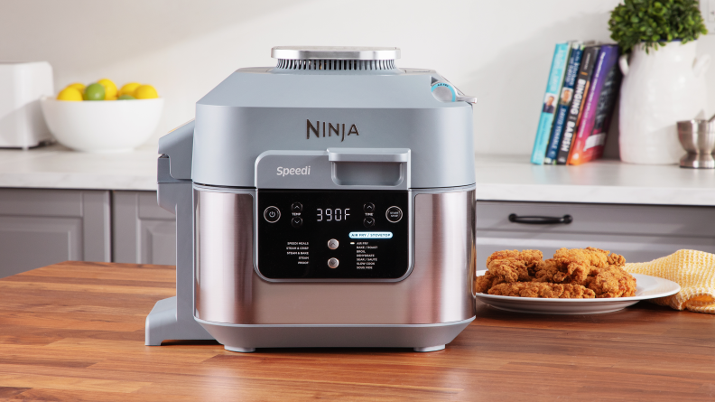 The Ninja Speedi air fryer sitting on a kitchen island next to a plate of perfectly air fried chicken.
