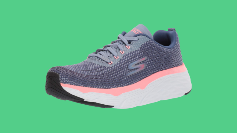 A pink and gray sneaker against a green background.