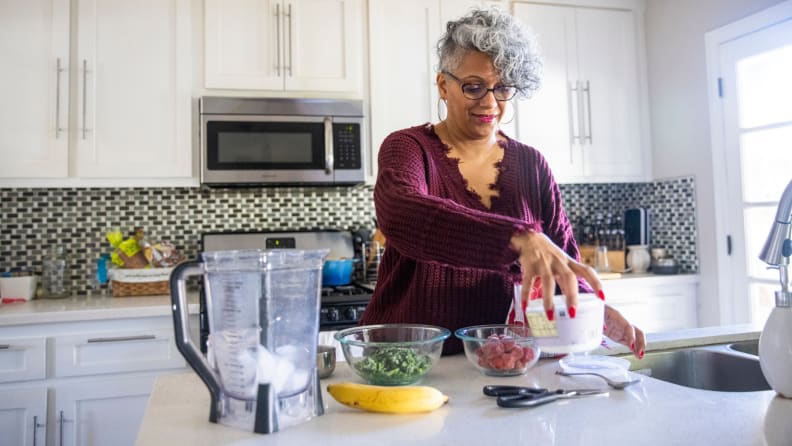 Older woman making a smoothie portion for one.