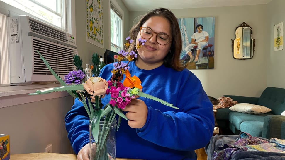 The Lego Flower Bouquet on a table being arranged by a person in a blue sweater.