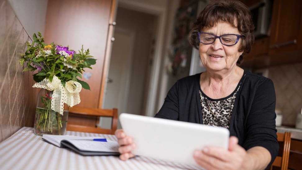 A senior looks at a digital tablet at home.