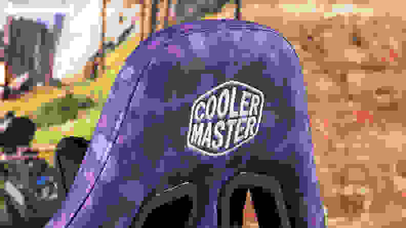 Close-up of the Cooler Master logo on the back of the gaming chair's headrest.