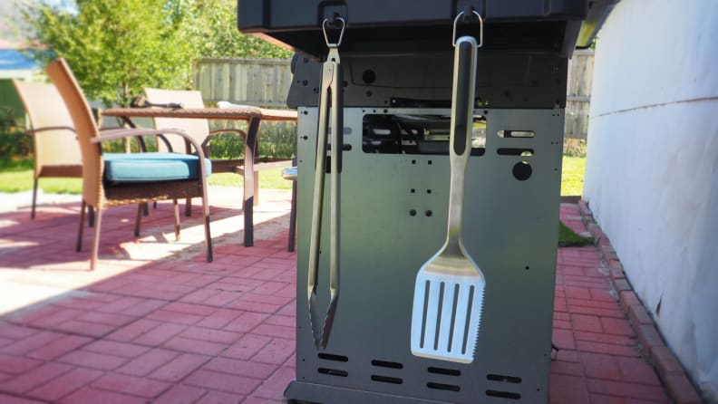 Grill spatula hanging from the side of an outdoor grill.