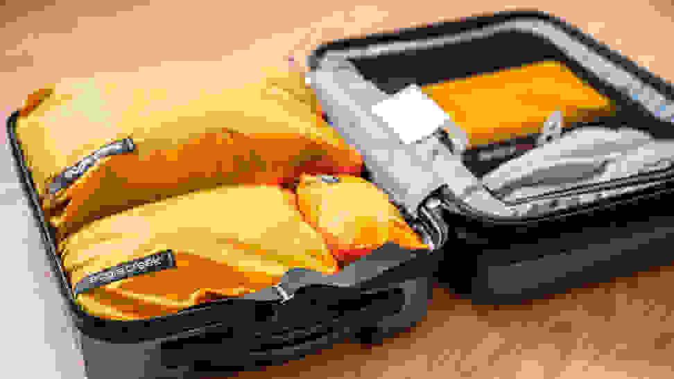An open suitcase filled with yellow packing cubes.