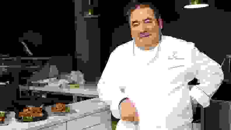 Emeril Lagasse standing by kitchen range