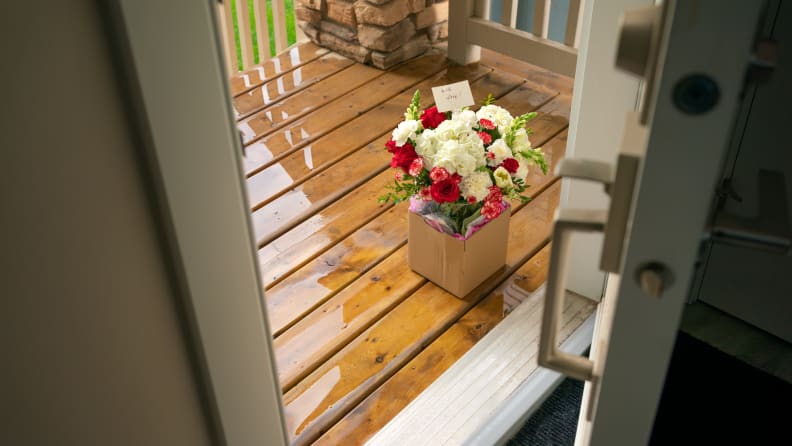 Flower arrangement sitting on ground on porch with front opened.