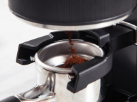 A close-up of a grinder ejecting coffee grounds into an espresso portafilter