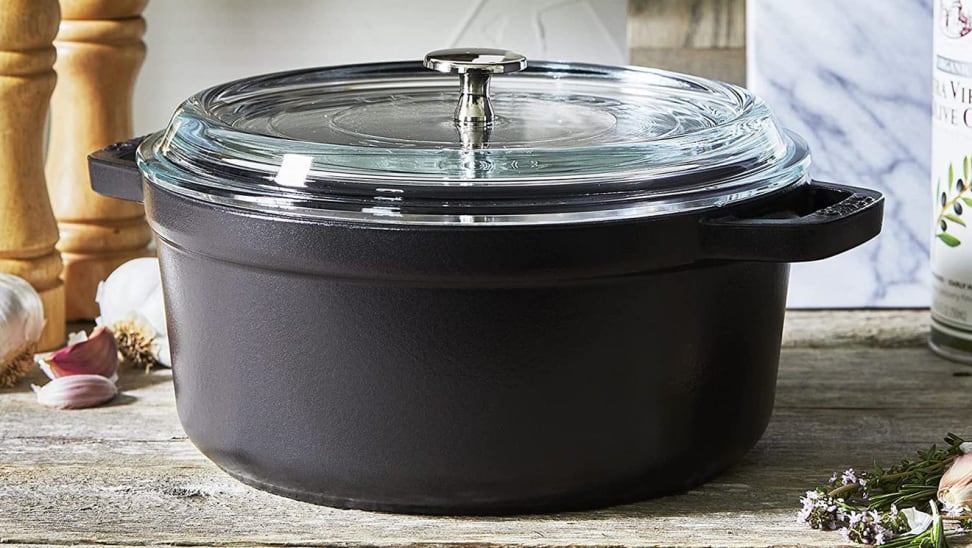 Black pot with clear glass lid on wooden countertop.