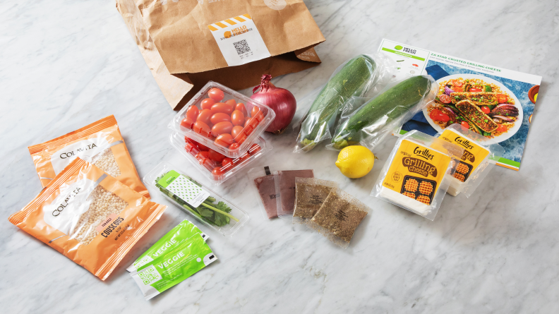 Several ingredients laid out beside a HelloFresh meal kit bag