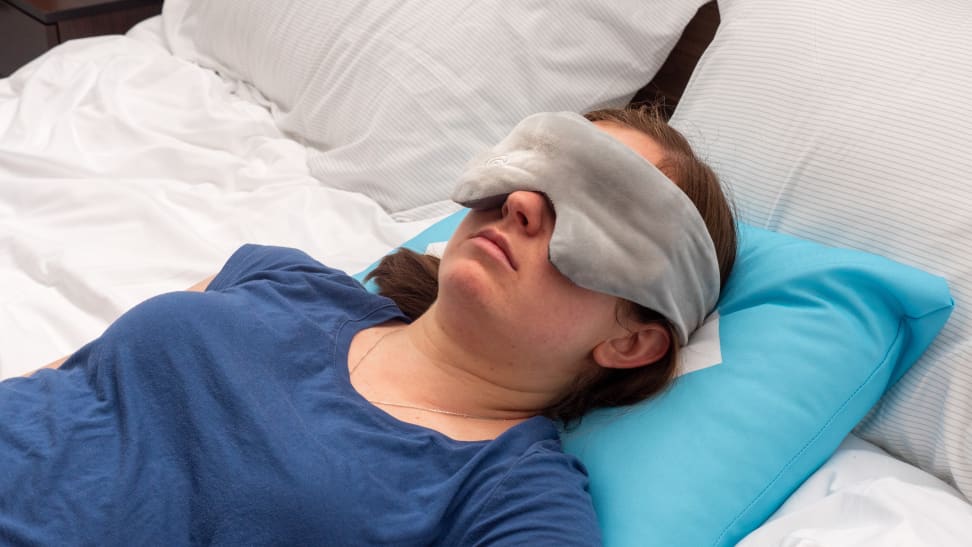 Person laying down on bed with weighted eye mask over eyes.