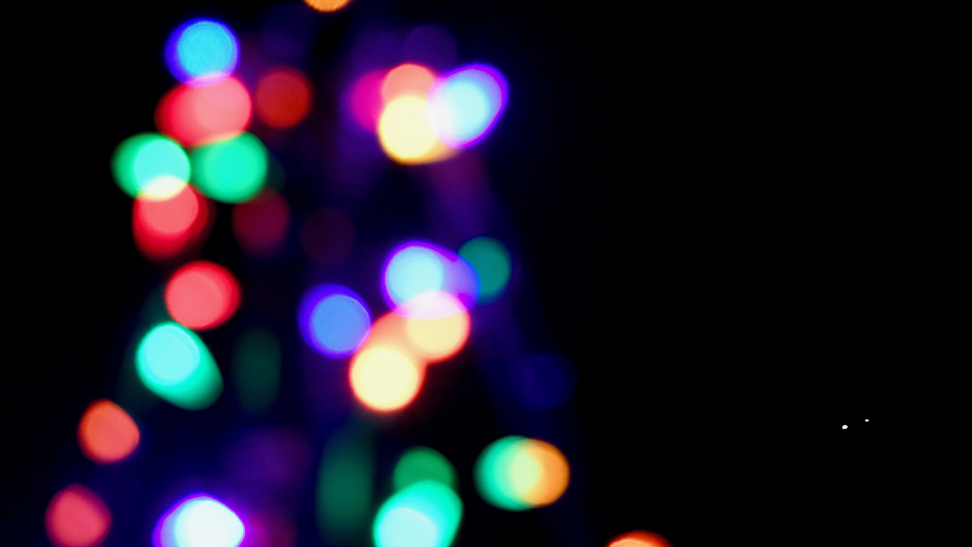 Colorful holiday lights are photographed out of focus.