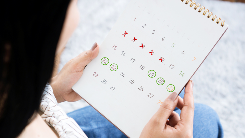 Person holding calendar with specific days circled in hands.