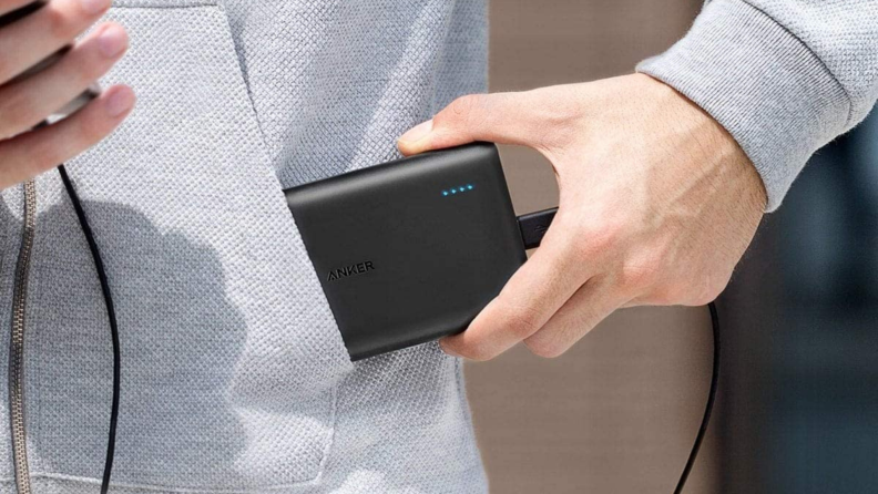 A person stuffs a portable charger in a pocket.
