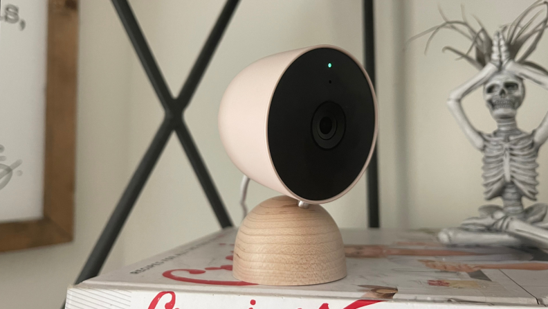 A Google Nest camera sitting on a living room shelf.