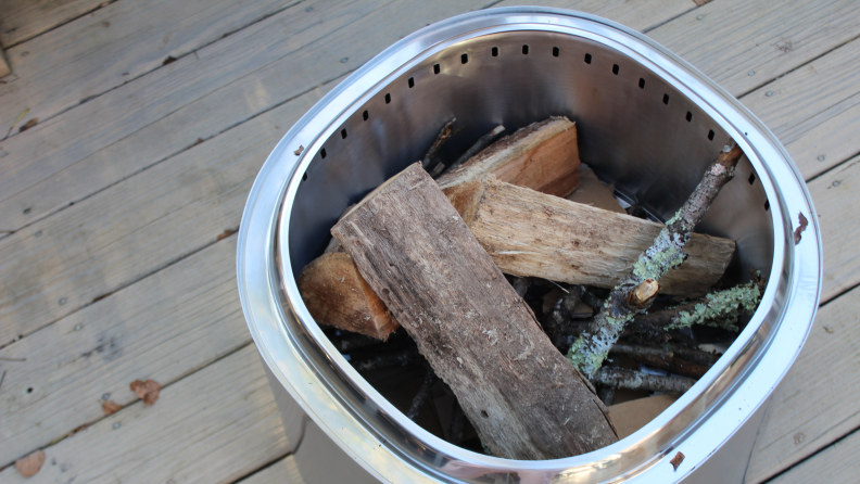 The East Oak Fire Pit viewed from above on a wood deck and filled with wood.