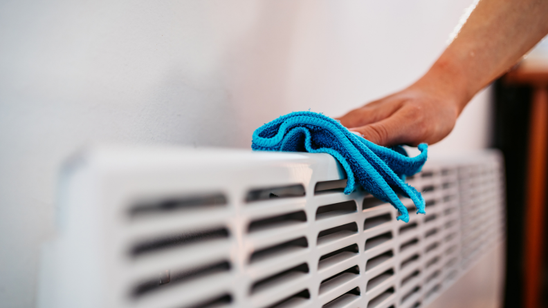 A person wipes a radiator with a cloth.