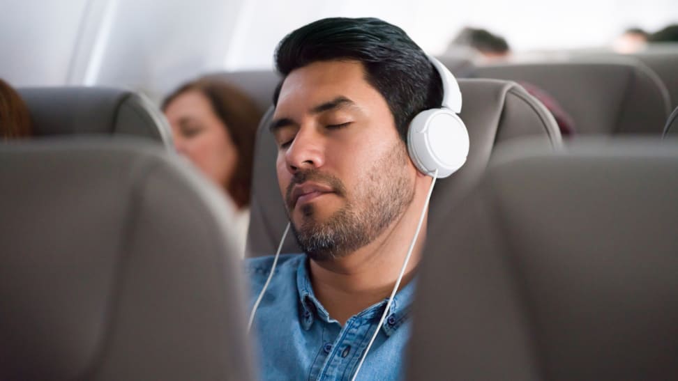 Man sleeping on plane with white headphones.