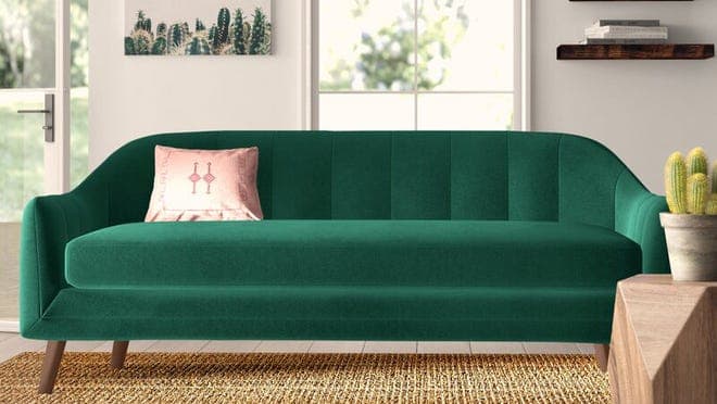 Emerald colored couch with pink pillow sitting in modern styled living room.