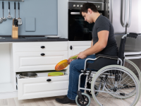 一个坐轮椅的男人在厨房里收拾盘子。