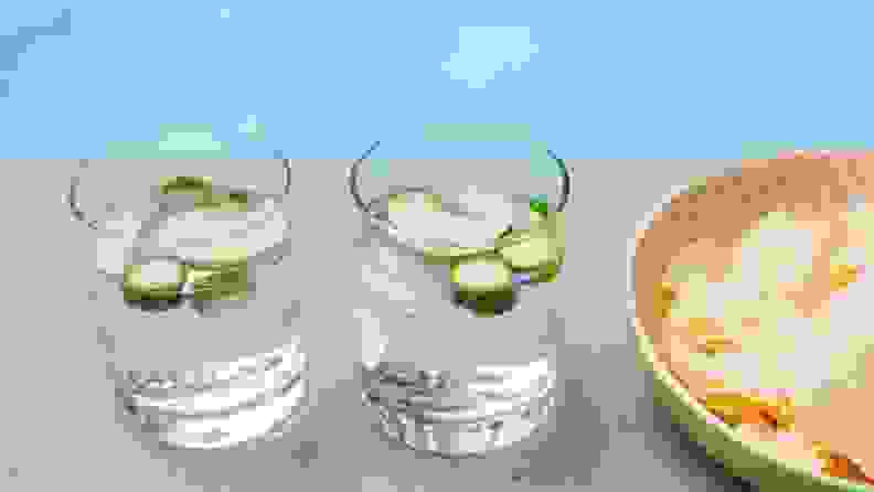 A pair of gin-and-tonics sit poolside next to a bowl of potato chips.