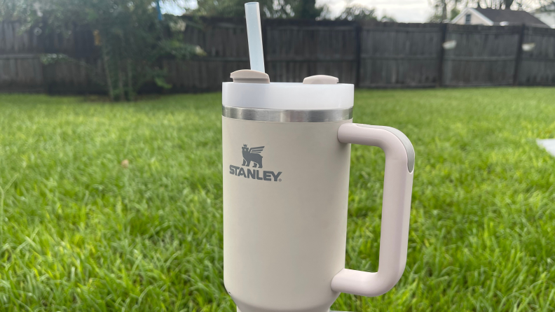 A white Stanley Quencher Tumbler sitting in the grass outside.