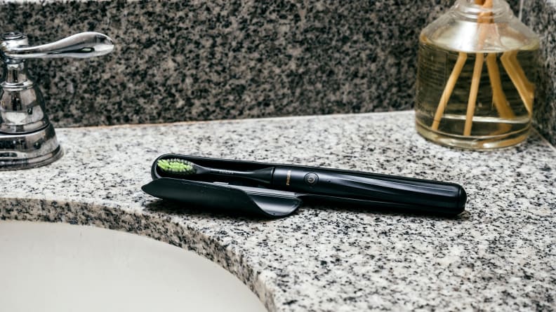 The Philips Sonicare One, our Bes Value Electric Toothbrush, lying in its case on a bathroom countertop.