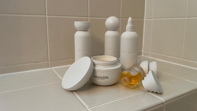 Many Cecred haircare products on a beige countertop.