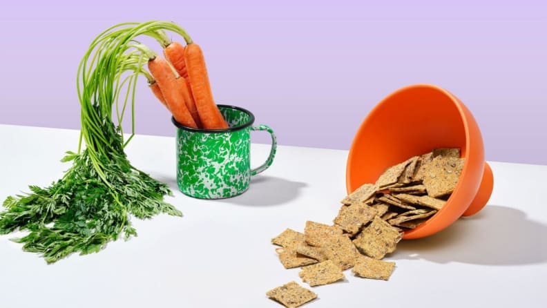 Bowls of carrots and chips sit on a surface.