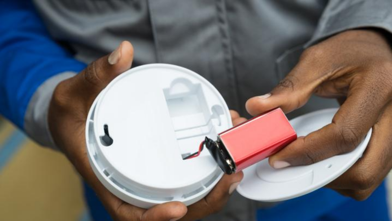 Man removing battery out of a smoke detector