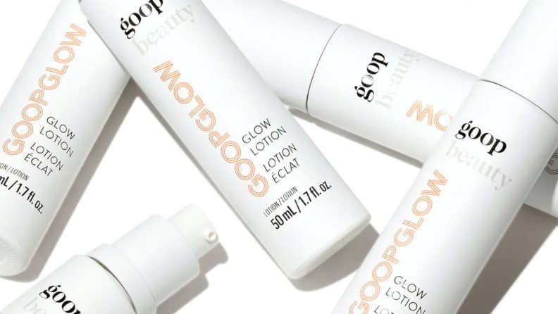 Several slim white bottles of moisturizer all laying on top of each other.