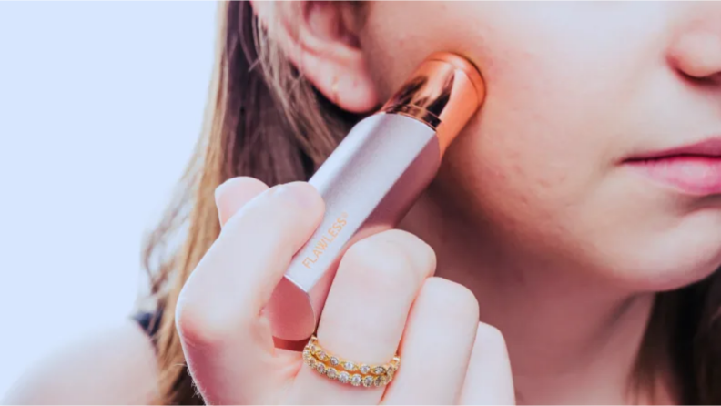 An image of a woman using the Finishing Touch Flawless hair remover on her cheek.