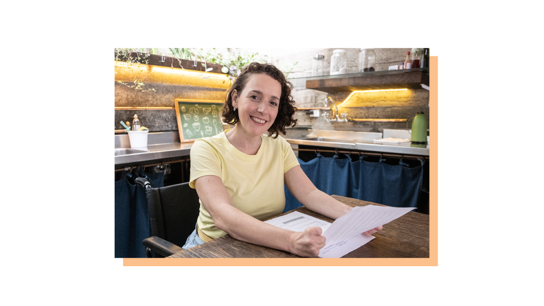 A woman with some government forms smiling.