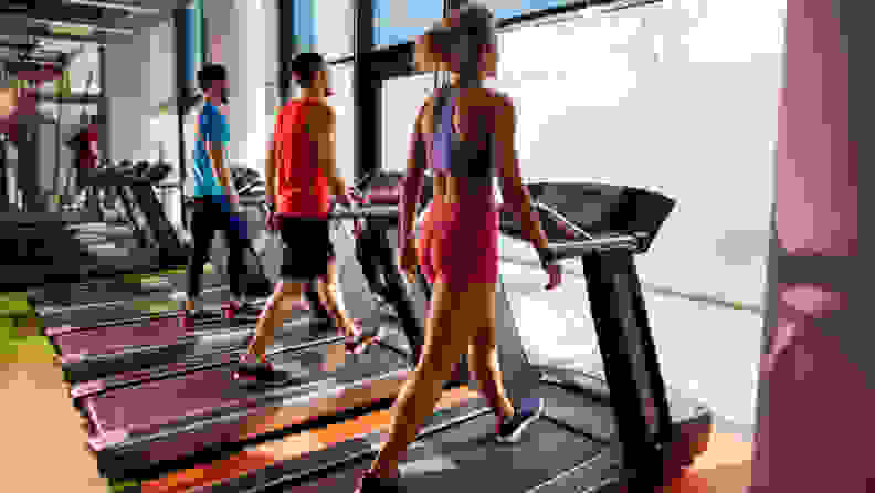 three people walking on treadmills