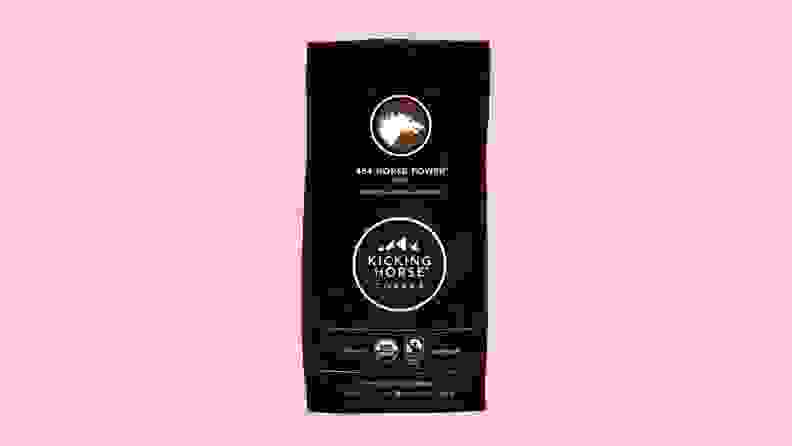 A bag of coffee grounds against a pink background.