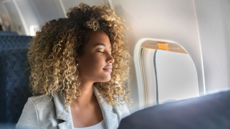 Woman sleeping against plane window